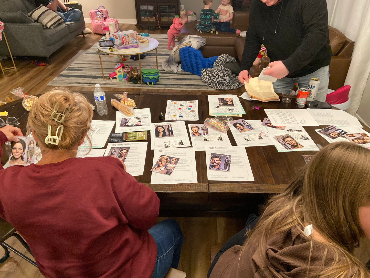 People sitting around a table with photos and snacks in a casual indoor setting playing the murder mystery box game