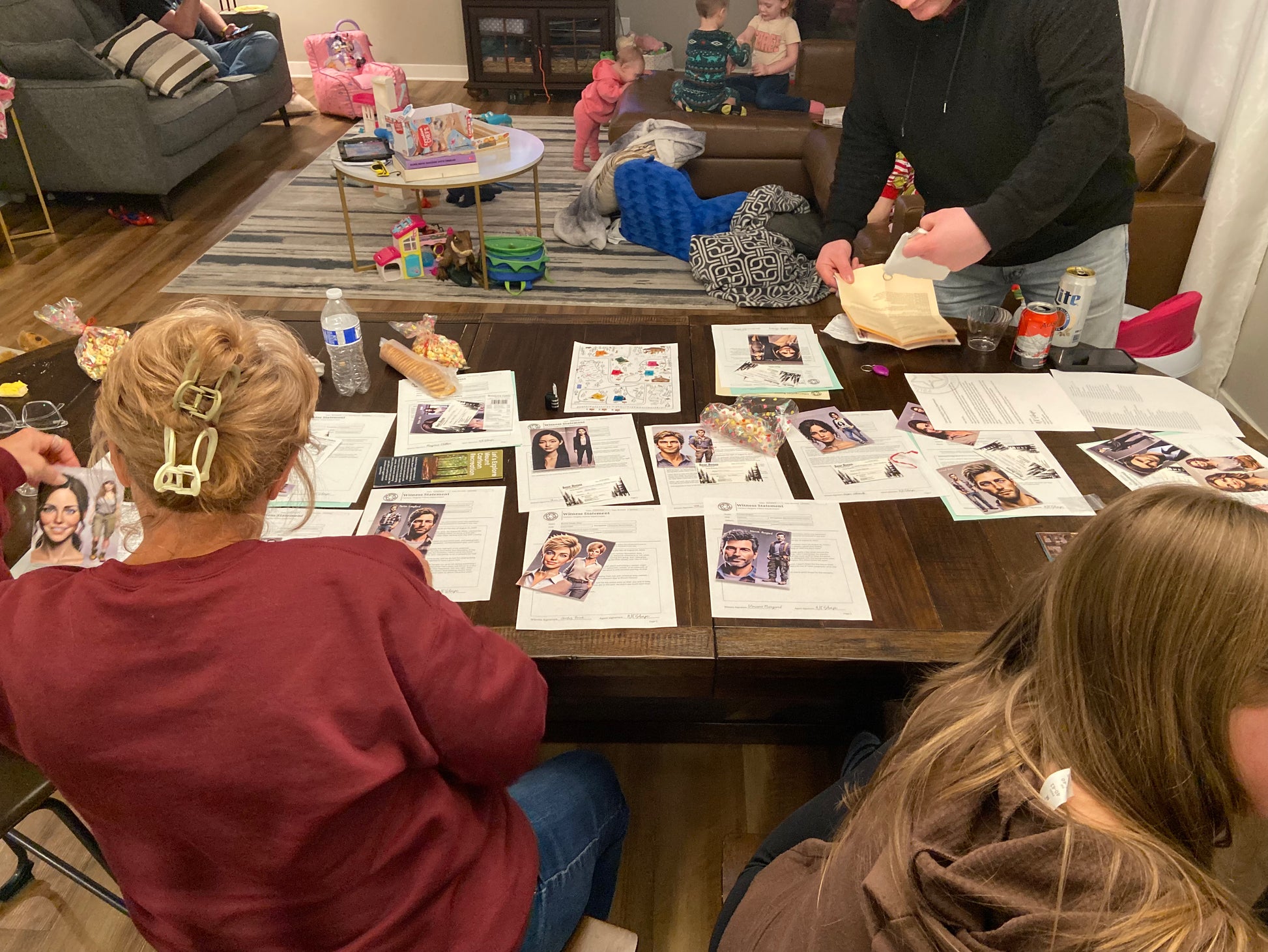 People sitting around a table with photos and snacks in a casual indoor setting playing the murder mystery box game
