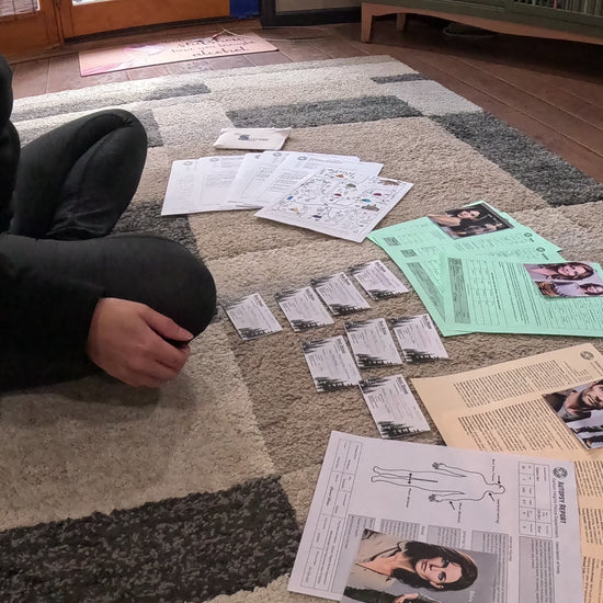 Video of person organizing Murder Mystery game box clues over the floor.